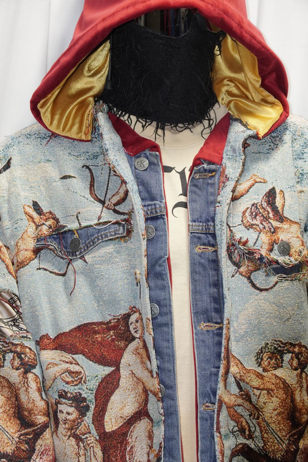 Front view of the reworked tapestry jacket over a cream tee, red velvet and gold satin hood lining