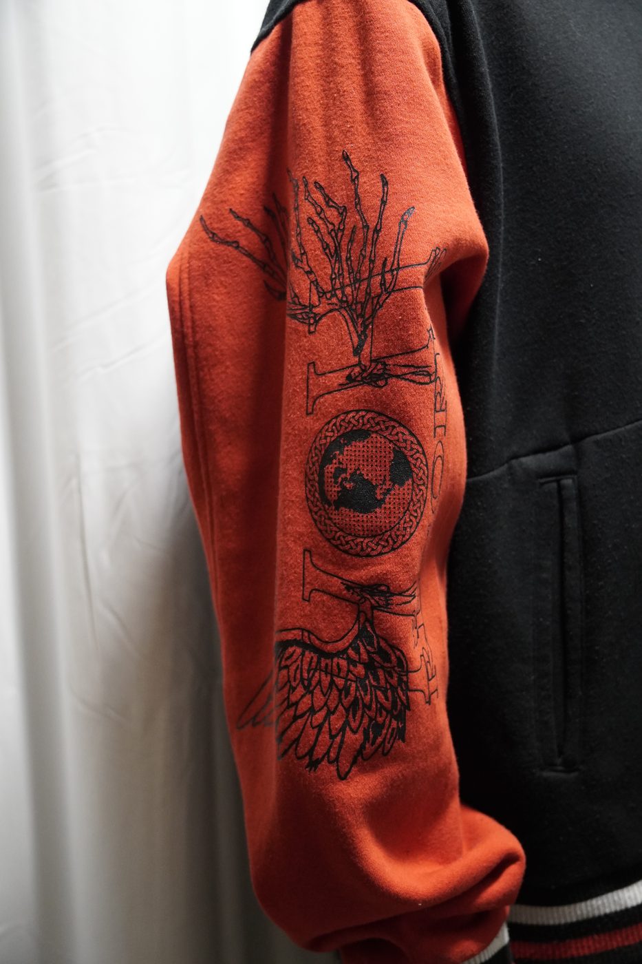 Orange and black varsity jacket with a Heaven or Hell Records graphic printed down the sleeve